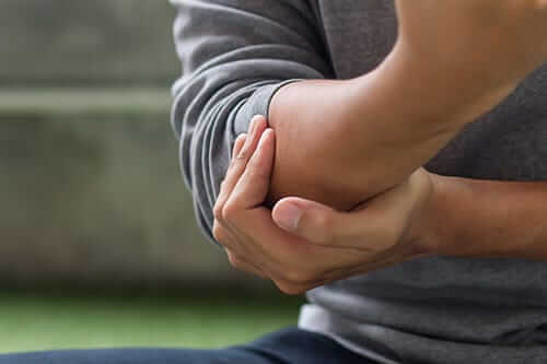 Person holding elbow may need an arthritis treatment center