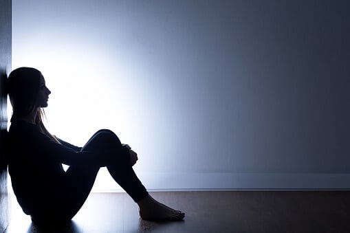 Woman against wall in dark coping with dual diagnosis