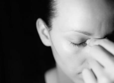 woman holding bridge of her nose wondering what is psychological dependence