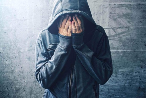 bereft man in hoodie exhibiting signs of addiction