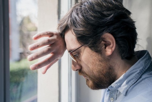 pensive man leaning head against hand against window needs anxiety treatment