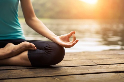 a woman finding the benefits of mediating near a lake