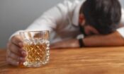 a man with his head down holds a drink and wonders when does binge drinking become a problem