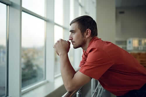 Pensive man looking out the window in need of a drug detox program