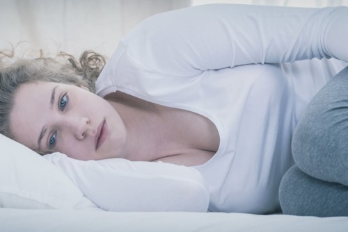 a woman struggling to get out of bed while dealing with dual diagnosis