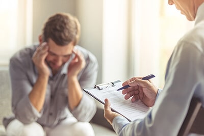 therapist taking notes of man struggling in evidence-based therapy