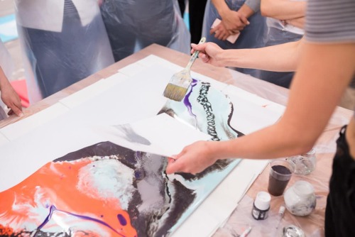 group of people watch another person paint in expressive arts therapy