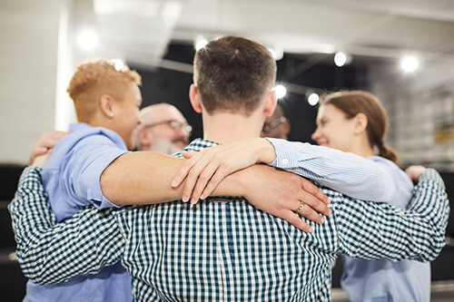 therapy circle with people putting arms around each others shoulders, healthcare professional addiction treatment center kemah tx