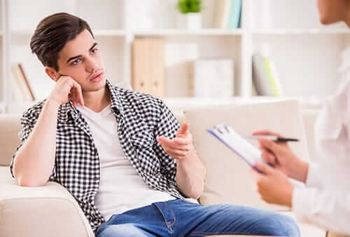 Young man on sofa speaking to counselor at our heroin addiction treatment center