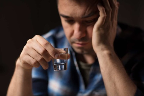 is-alcohol-a-drug a man taking a shot wondering is alcohol a drug