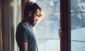 man focuses and looks out window during national recovery month