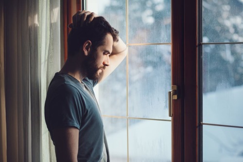 man focuses and looks out window during national recovery month