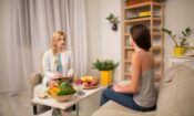 a nutritionist talks to a female patient about nutrition and addiction recovery with fruits and vegetables on the table