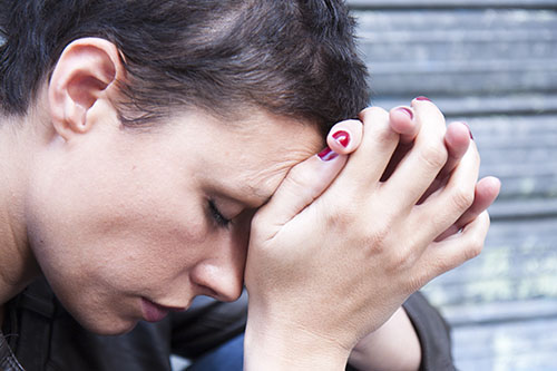 Depressed woman clasping hands looking for an oxycontin addiction treatment center