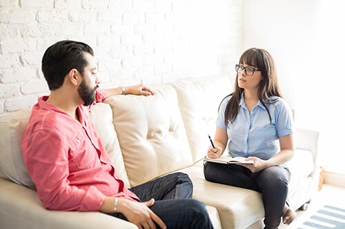 Female therapist talking with bearded client during relapse prevention therapy