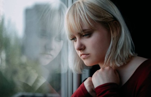 pensive young woman looking out a window thinking about how to recognize unhealthy coping skills