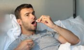 man in bed taking a pill wondering what is the opioid crisis