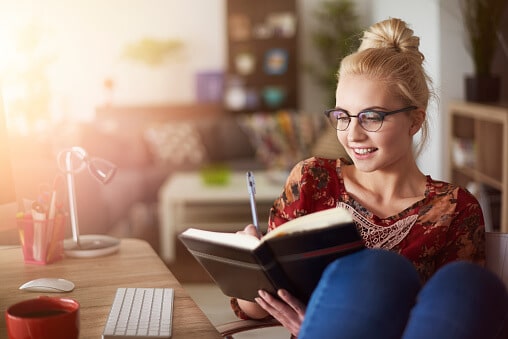 Woman sitting at her desk riding in her journal