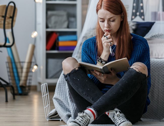 woman sitting in front of her bed journaling