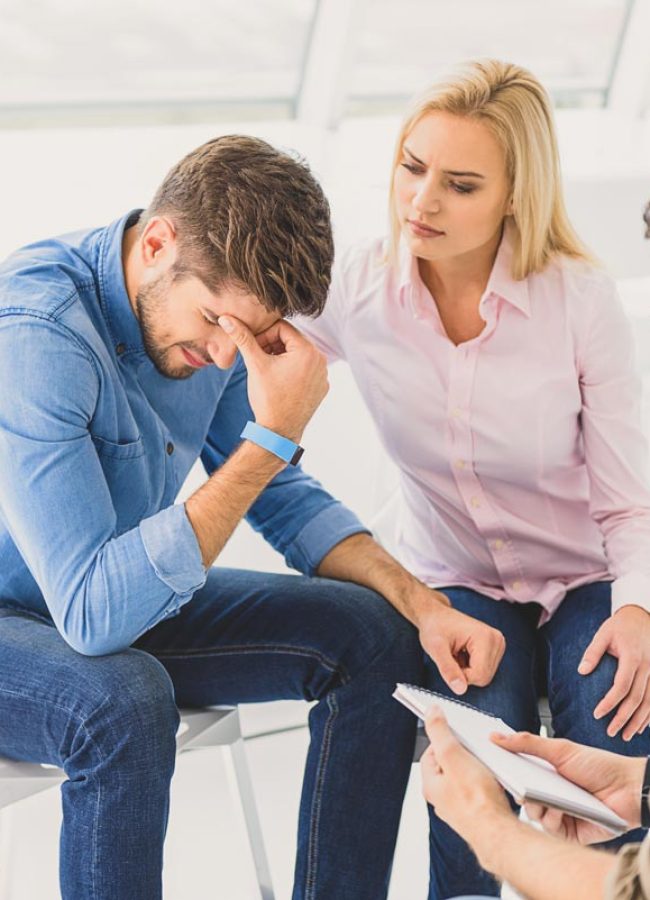 Man sitting with his wife speaking with his therapist during his psychodrama therapy addiction treatment