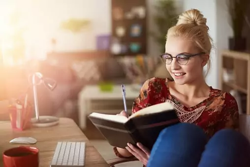 Woman sitting at her desk riding in her journal