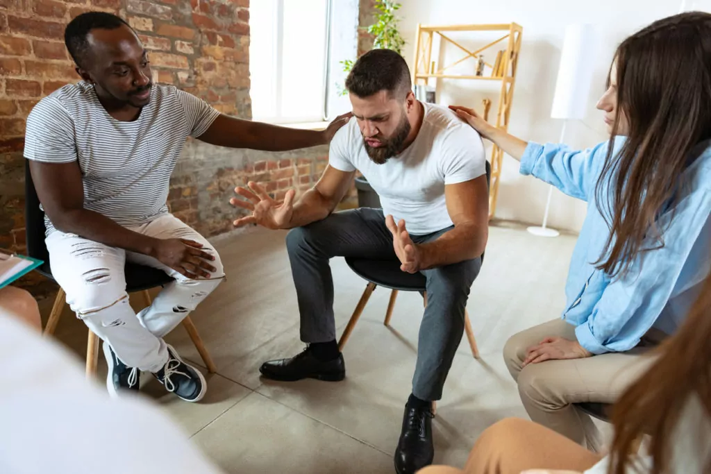 man and woman embracing another man during Addiction Therapy Services in Houston