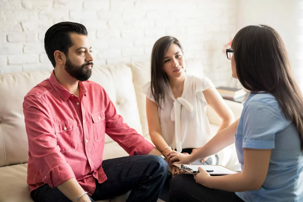 male and female sitting on a couch with their therapist discussing dual diagnosis treatment