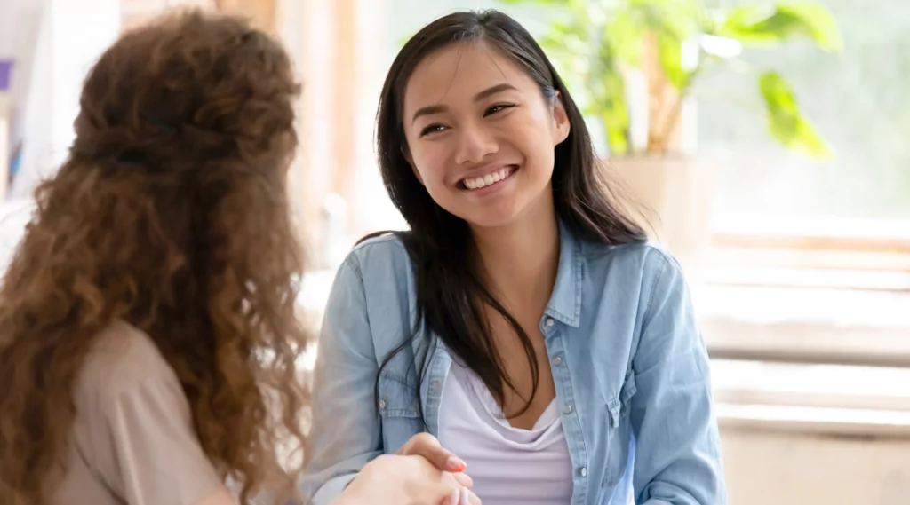 Two women sitting down and They are talking and listening to each other.
