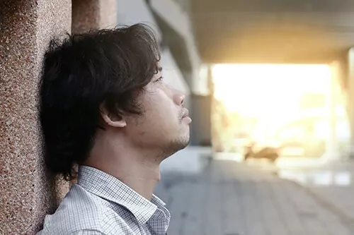 Man leaning against the wall, staring up, looking sad