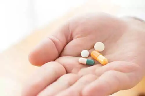 man holding a handful of pills needing opiate detox