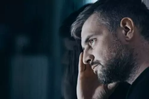 Man, staring at the window, holding his head, dealing with painkiller withdrawal