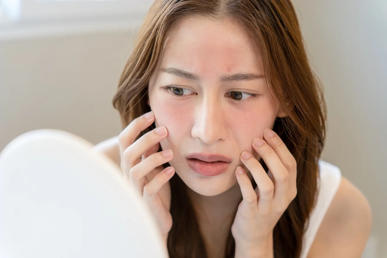 woman looking in the mirror wondering How to Spot an Alcoholic Face
