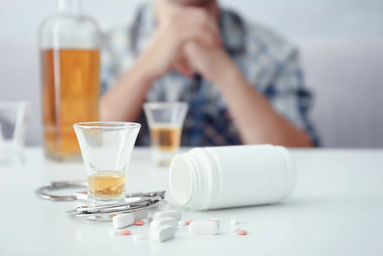 man holding his head sitting on the couch struggling with side effects of mixing gabapentin and alcohol