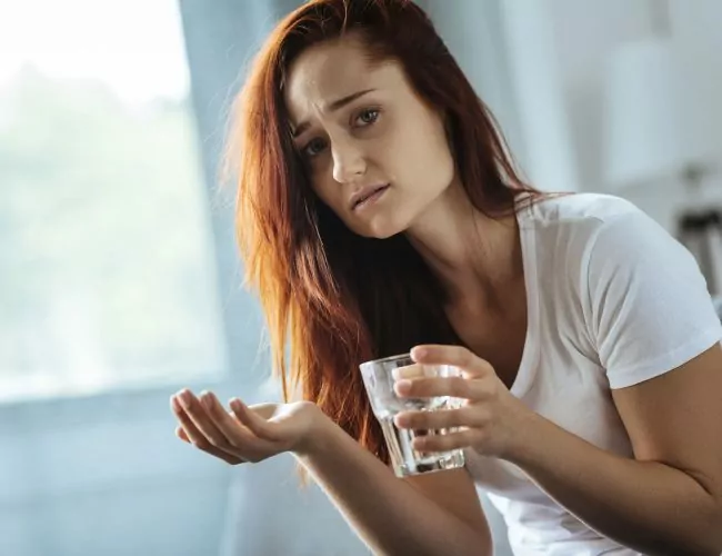 woman struggling with addiction getting ready to take another pill.